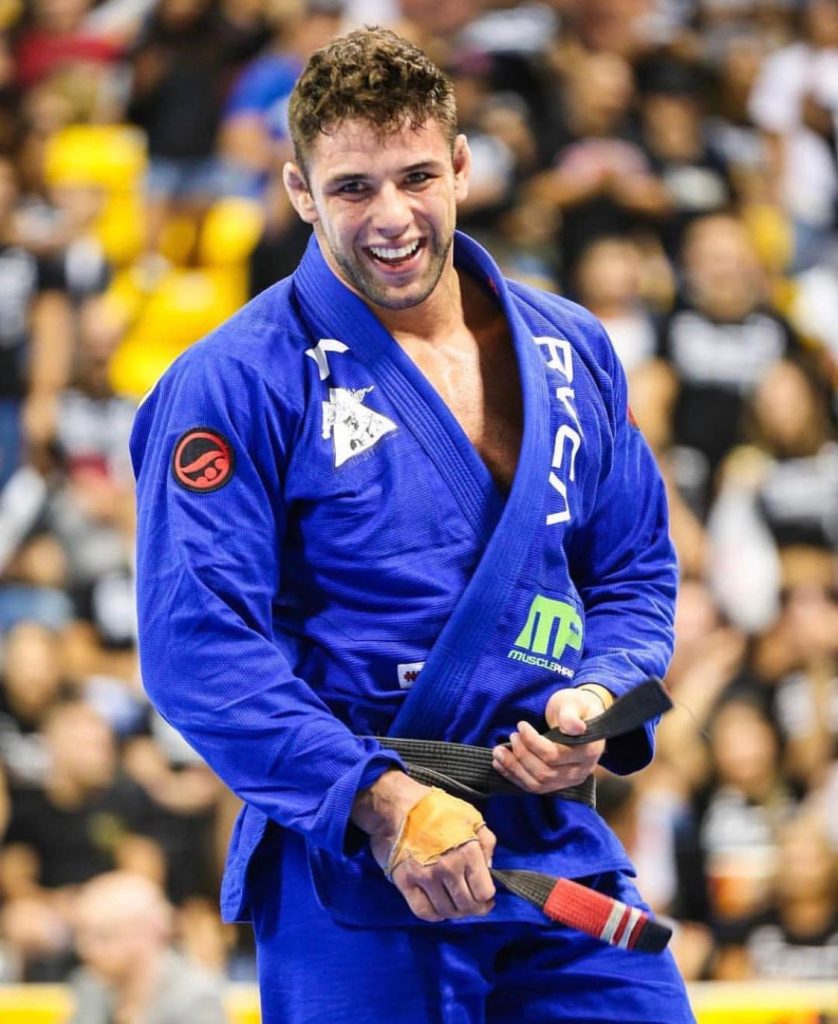 Marcus "Buchecha", black belt professor, in a blue gi tying his black belt after a competition match